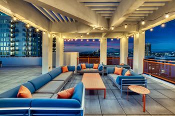 a rooftop lounge with blue couches and orange pillows